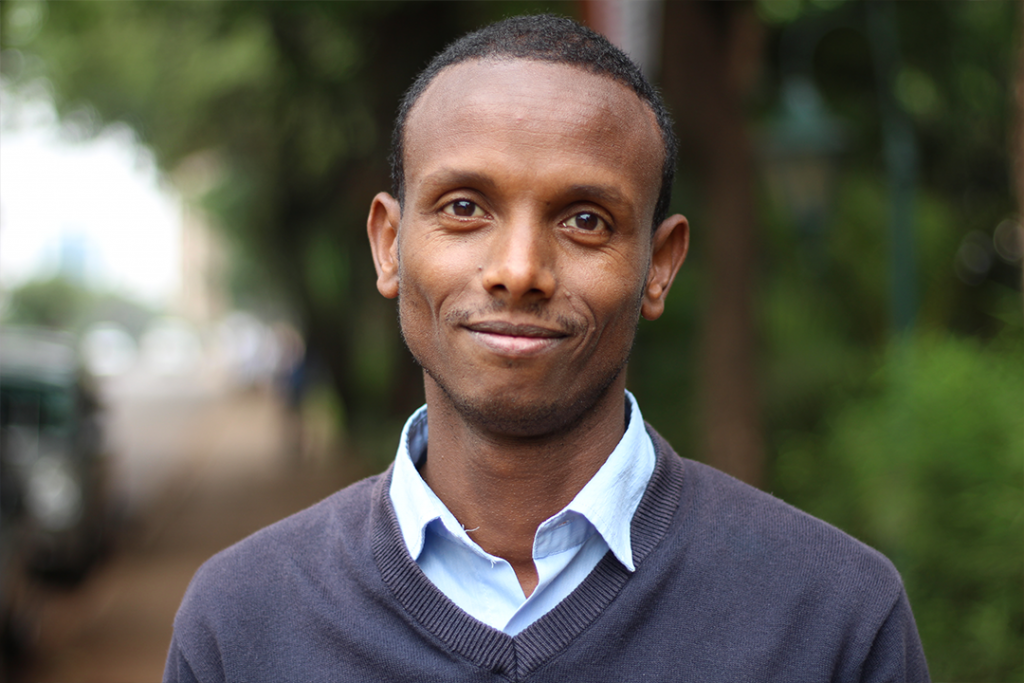 Befekadu Hailu Techanie smiling in front of green trees.