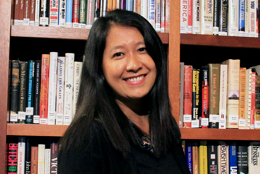 Esther Htu San stands in front of a bookshelf.