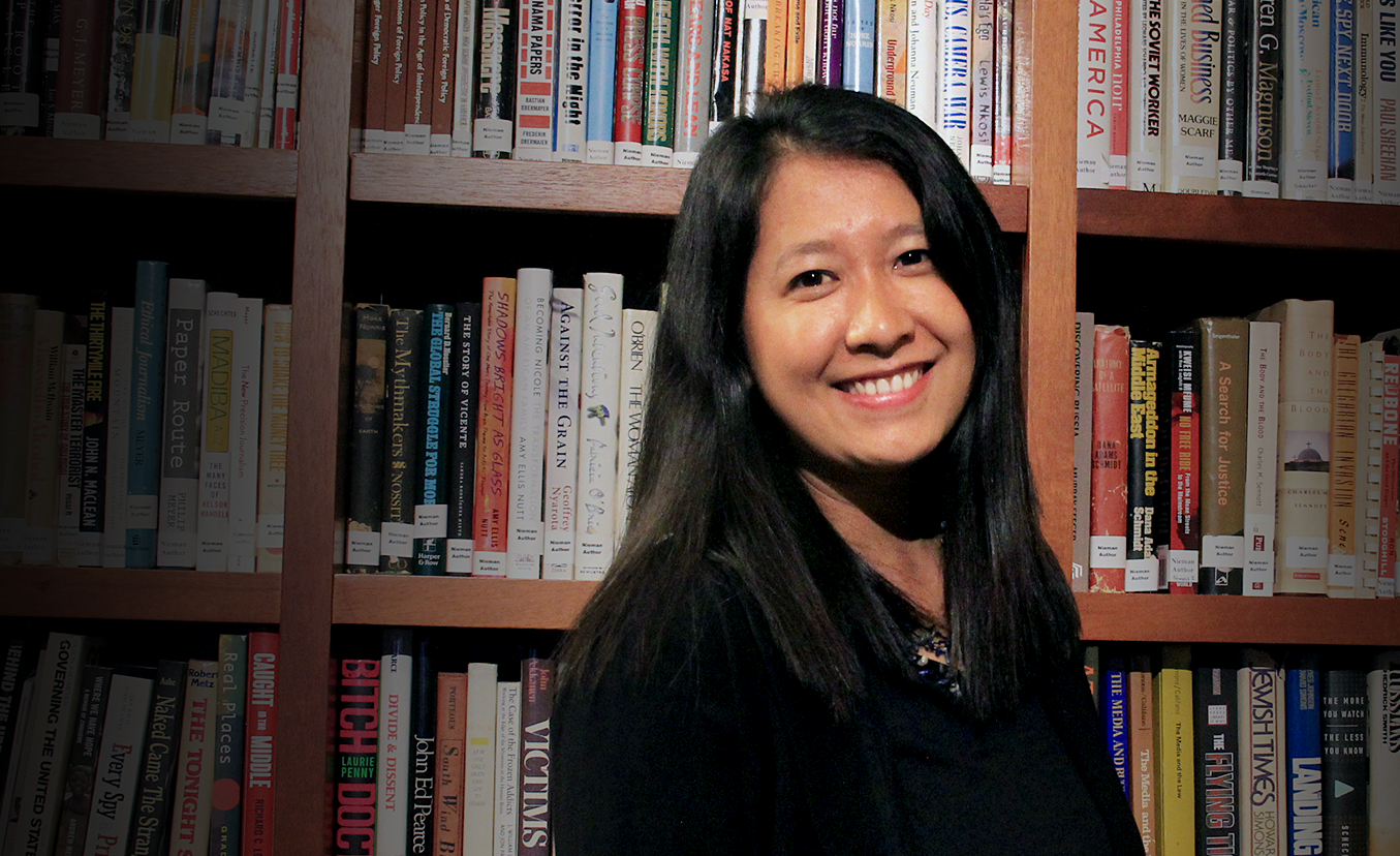 Esther Htu San stands in front of a bookshelf.