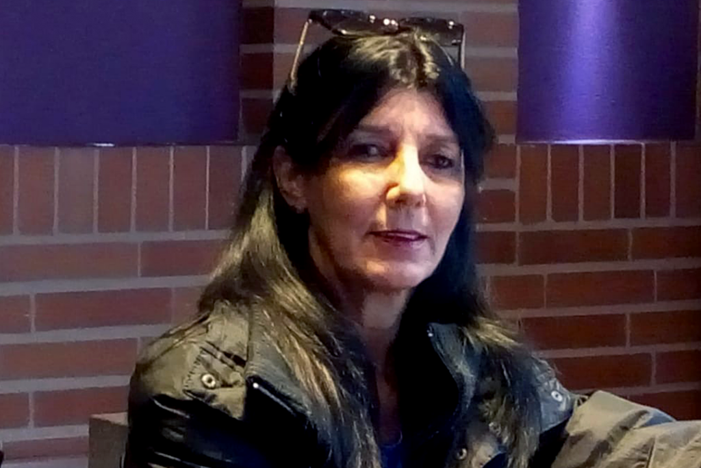 María Elena Mir Morrero sitter framför en tegelvägg i en skinnjacka.