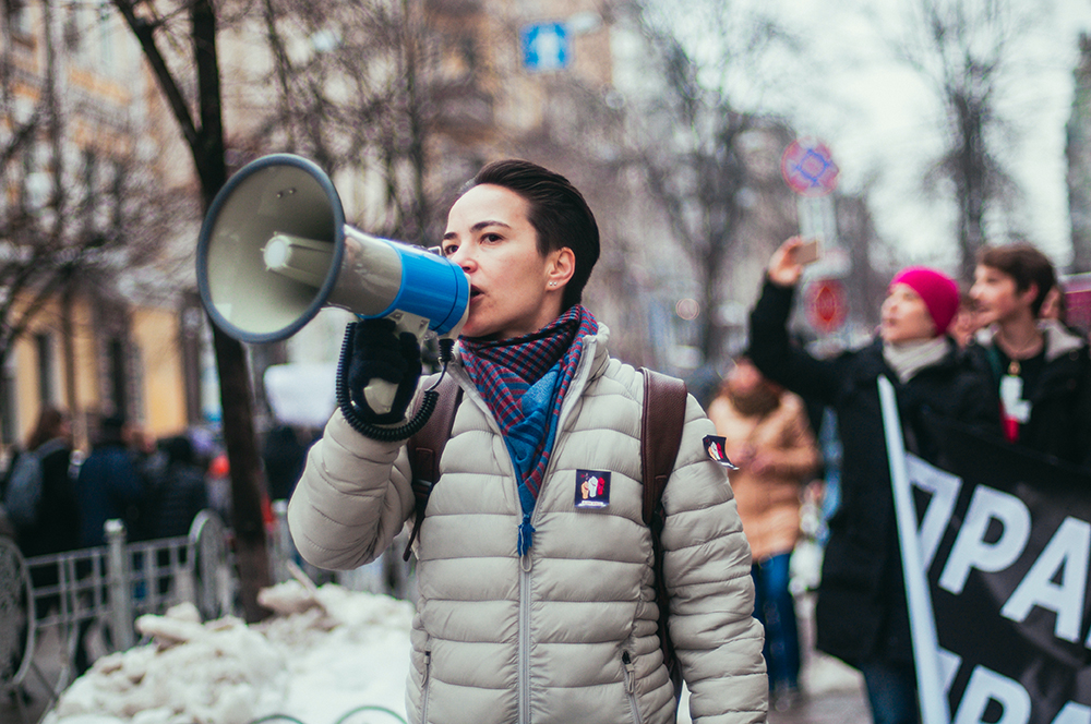 Olena Shevchenko speaking in a megaphone during a demonstration.