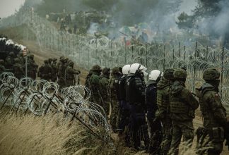 Soldiers standing in front of a fence.