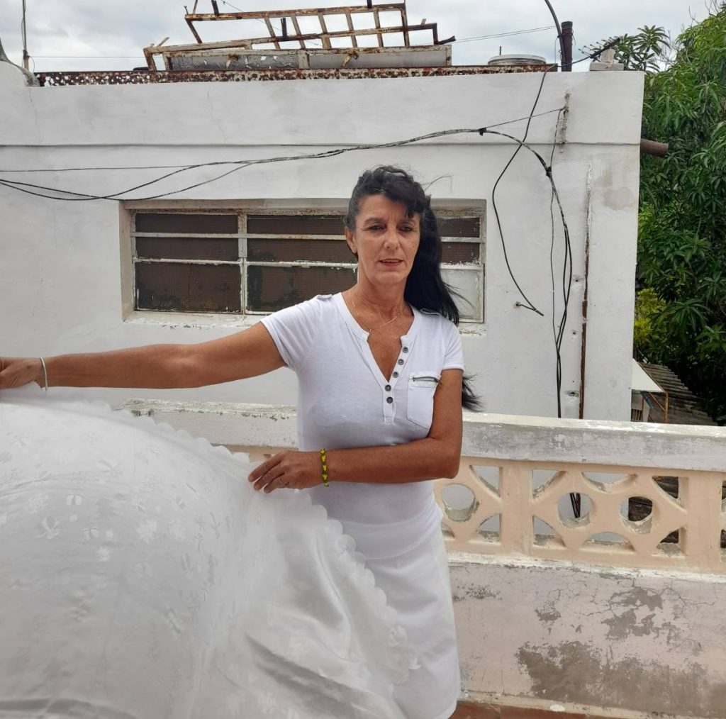 Woman standing on her roof dressed in white.