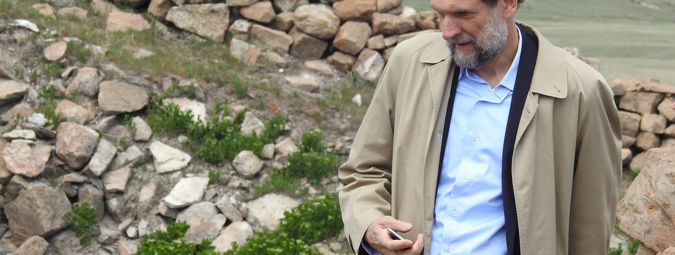 Osman Kavala walking along stone walls in hilly scenery