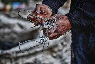Hands holding metal wires illustrating lead poison Kosovo