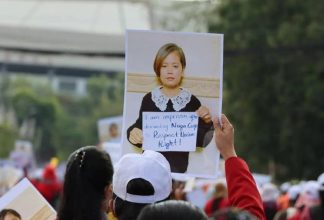 A protester holds up a picture of Sithar Chhim holding up a poster that says, 
