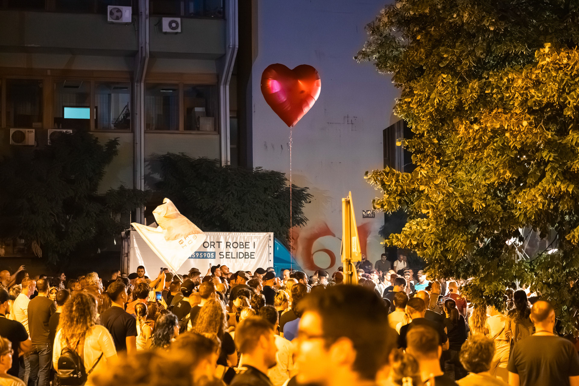 A large crowd of protesters in Serbia, with a red heart-shaped balloon rising above them.