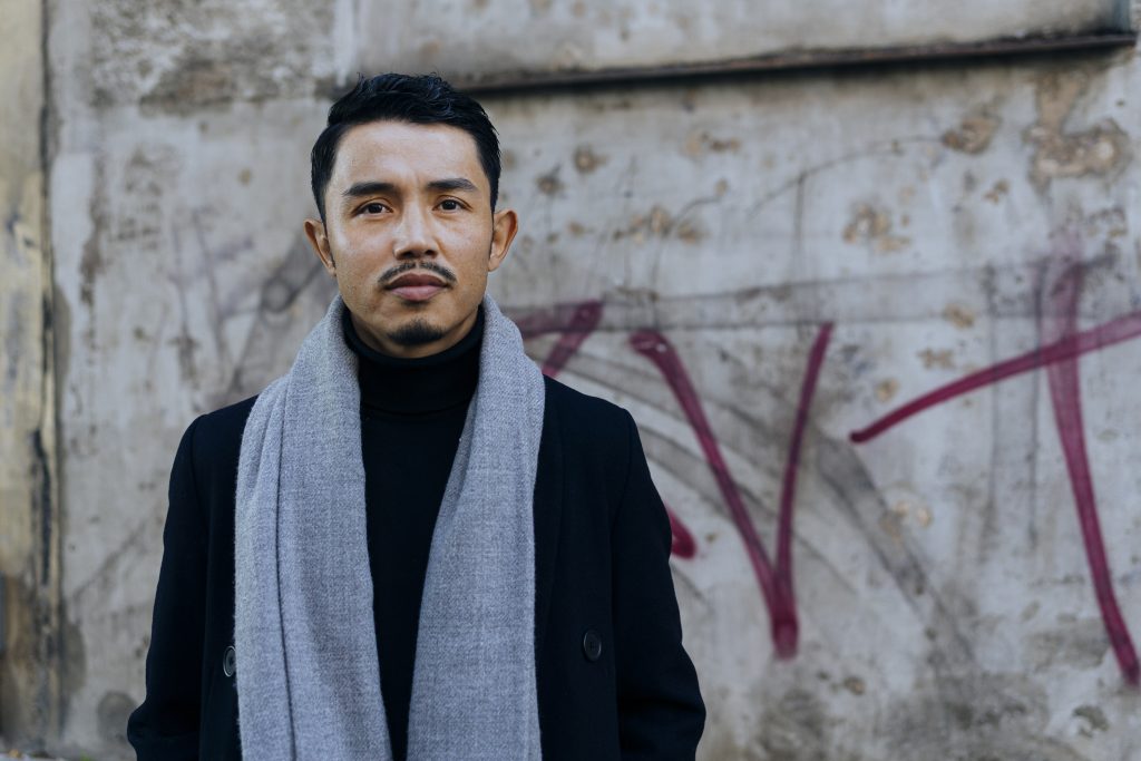 Ali Yusefi stands against a concrete background in Stockholm, looking into the camera with a neutral expression.