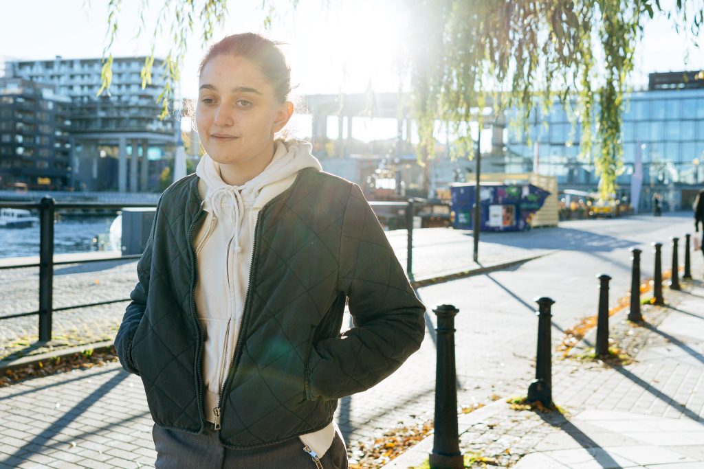 Silvi Aduorian standing outside, with the sun shining behind her looking into the camera with a friendly expression.