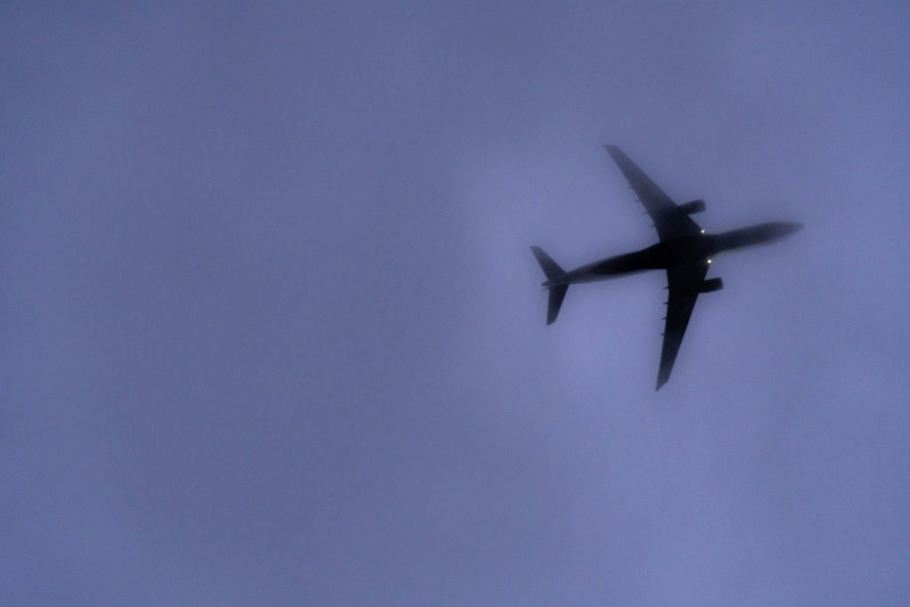 A blurry airplane against a dark blue sky, seen from underneath.