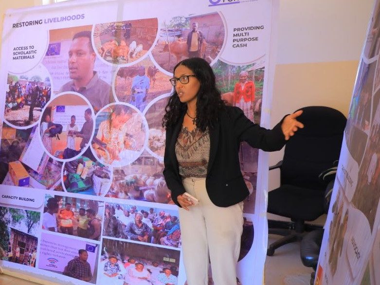 A young woman holding a lecture or workshop in front of a banner, in an office space
