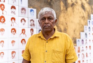 Brito Fernando framför ett monument med hundratals porträtt av ofrivilligt försvunna i Seeduwa utanför Colombo. Foto: Forum för levande historia/Splendid