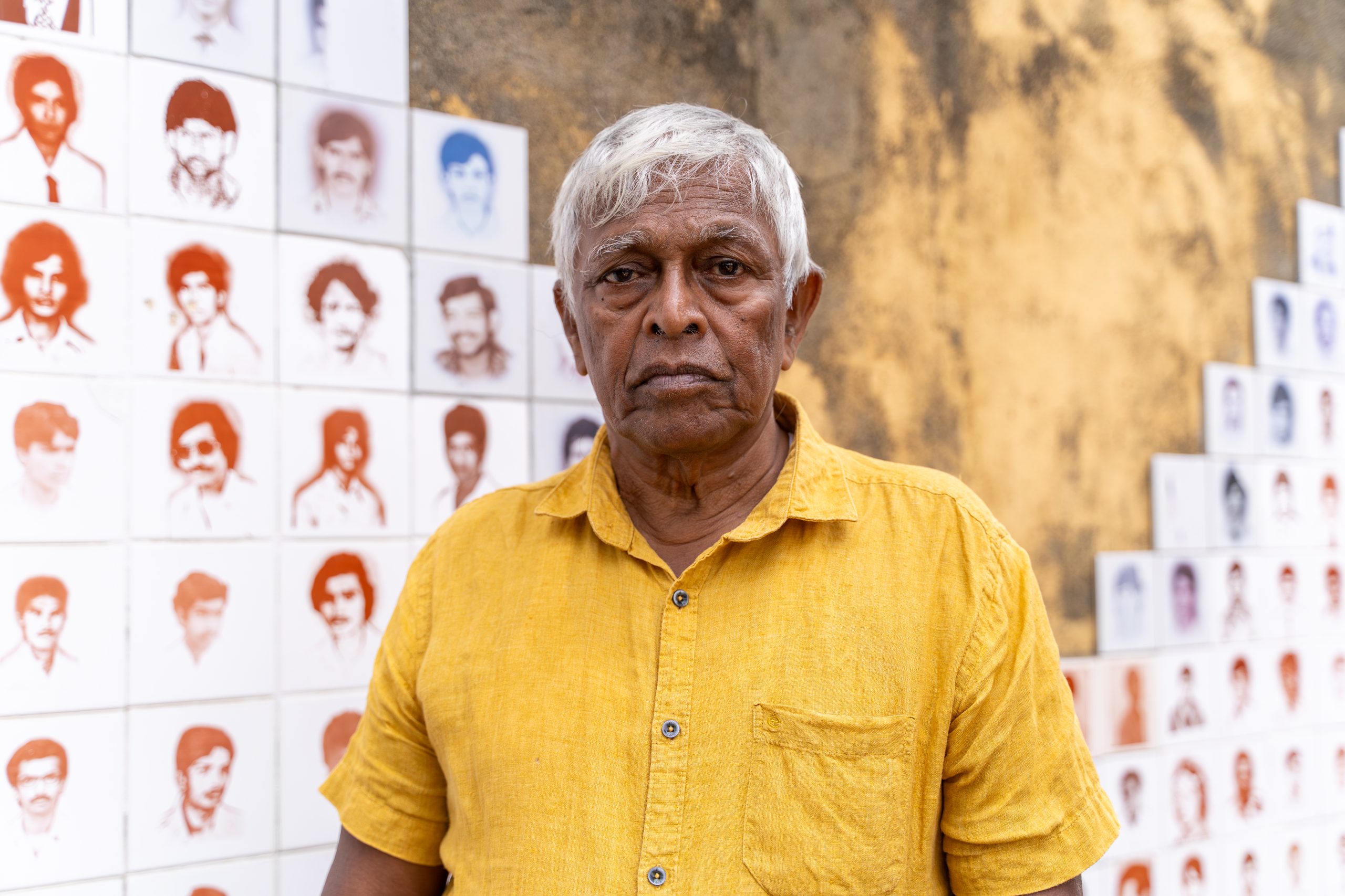 Brito Fernando framför ett monument med hundratals porträtt av ofrivilligt försvunna i Seeduwa utanför Colombo. Foto: Forum för levande historia/Splendid